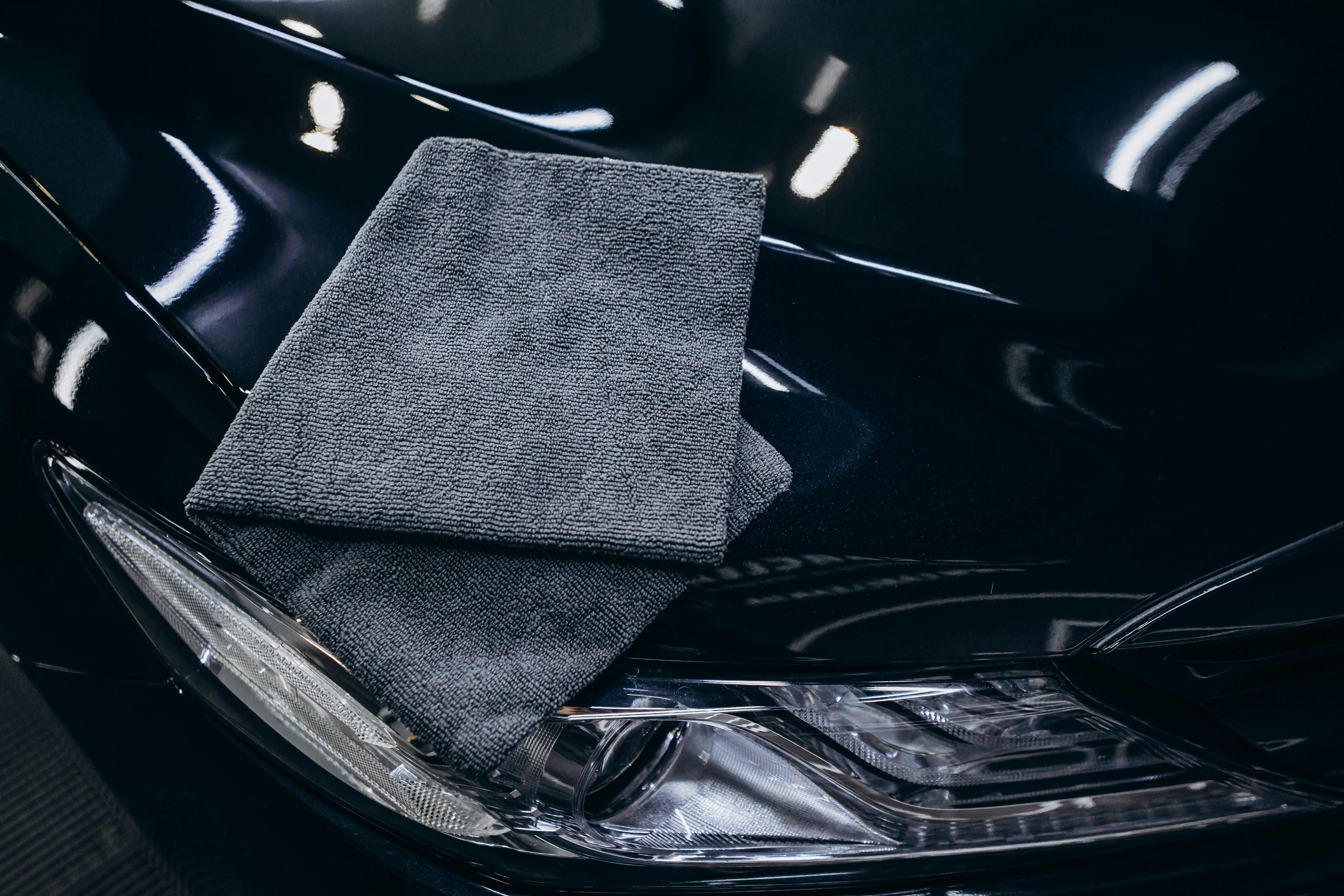 Freshly detailed car paint with water beads and a microfiber cloth